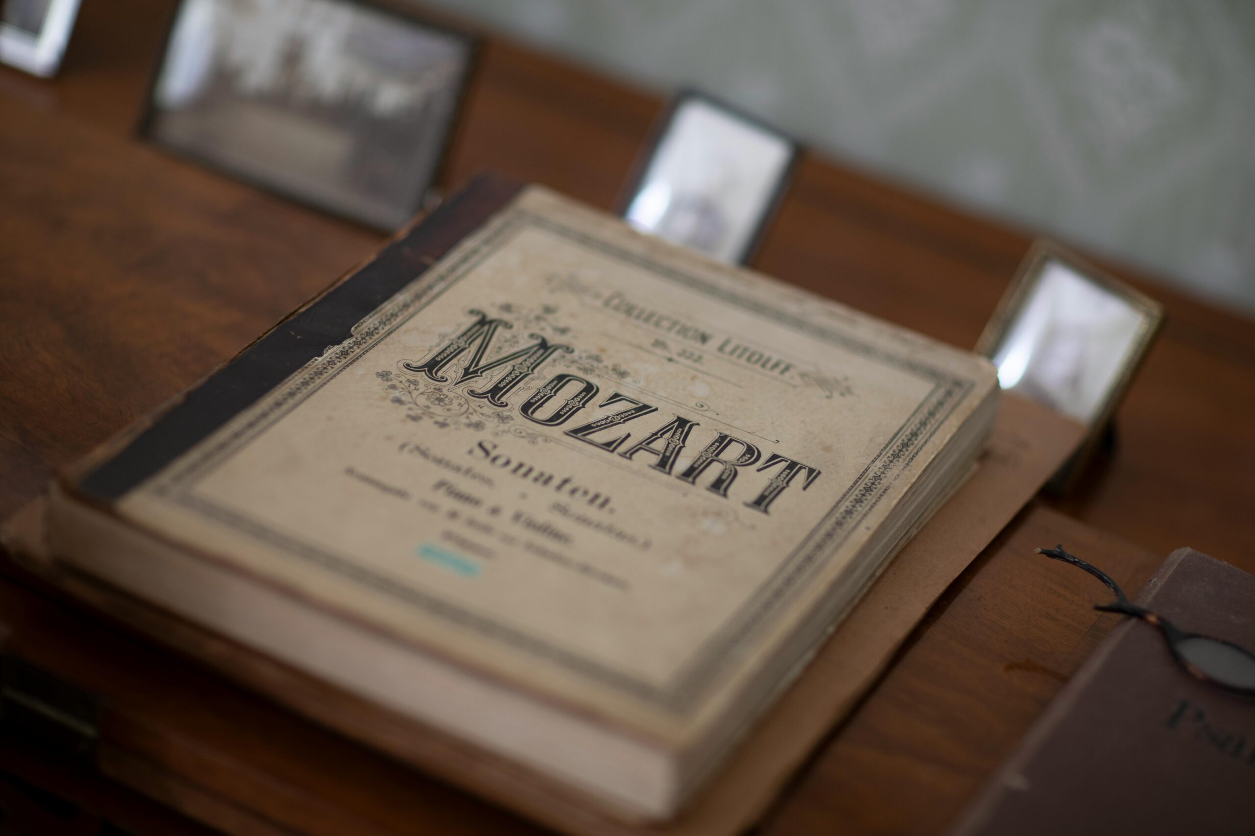 An antique book displaying Mozart's sheet music on a vintage table setting.