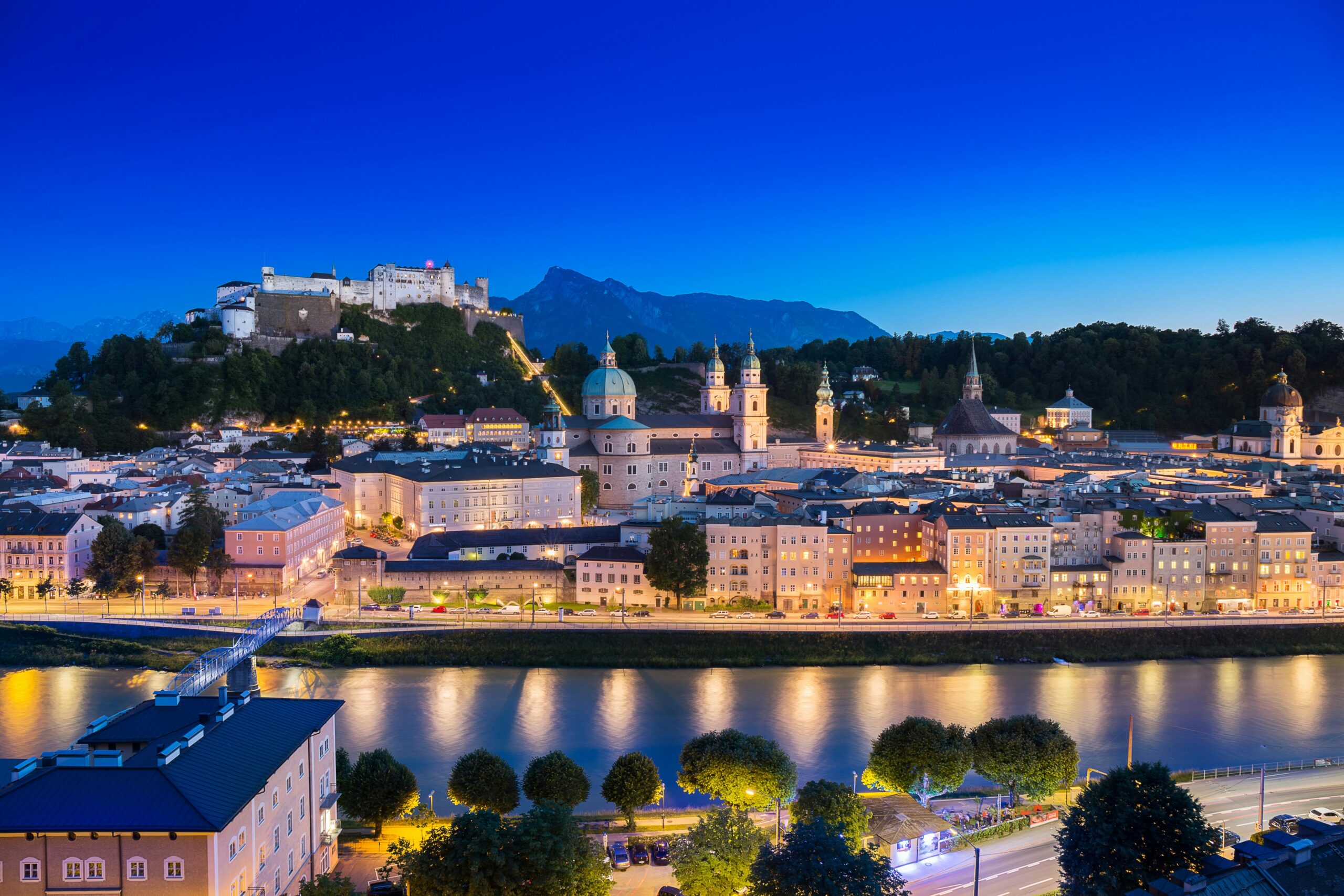 A breathtaking view of Salzburg cityscape with the illuminated Hohensalzburg Fortress at dusk.
