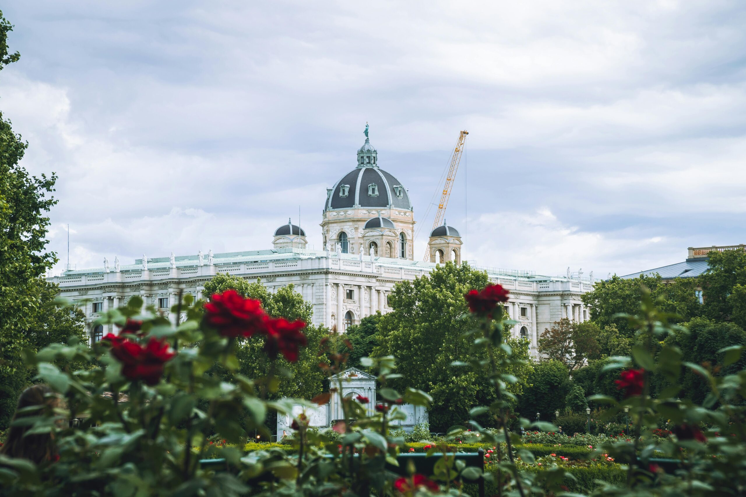 View of Vienna's Kunsthistorisches Museum with garden roses and greenery in the foreground.